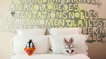 Uma cama com dois travesseiros, um com um pato de desenho animado e outro com um coelho.