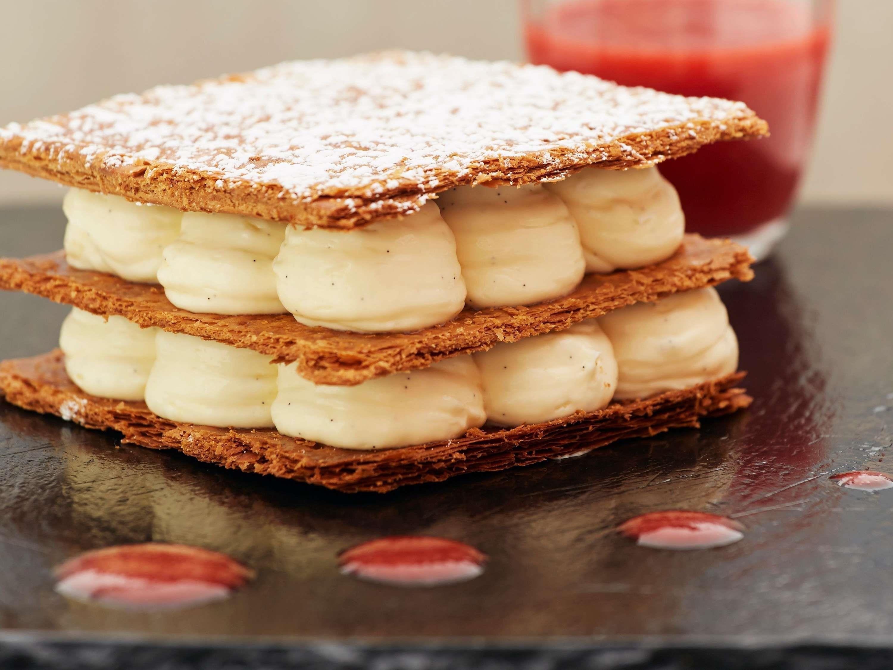 Una pila de postres en capas con azúcar glas por encima.
