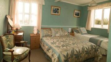A bedroom with a bed, two bedside tables, a chair, and two windows with curtains.