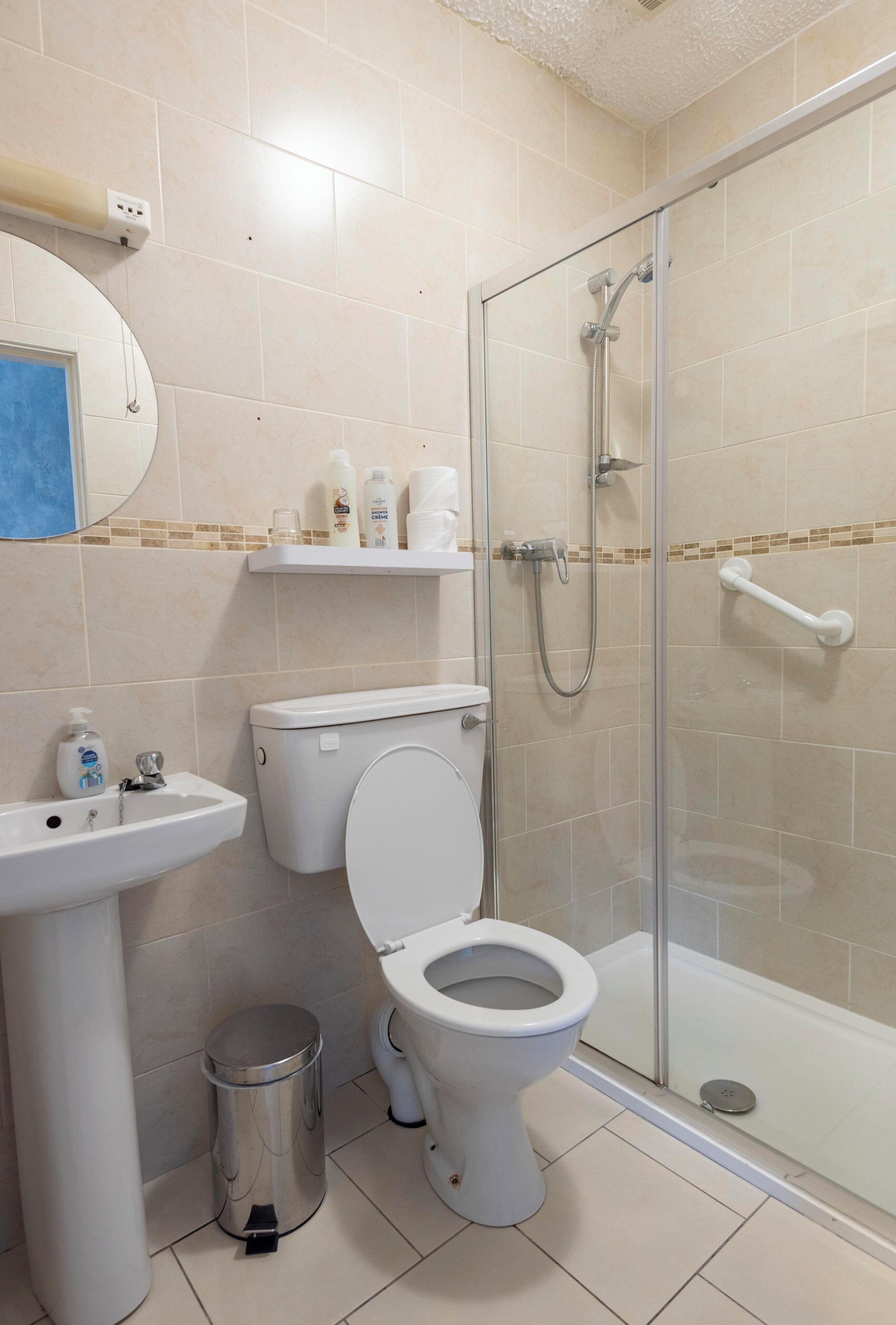 A bathroom with a toilet, sink, and glass-enclosed shower stall.