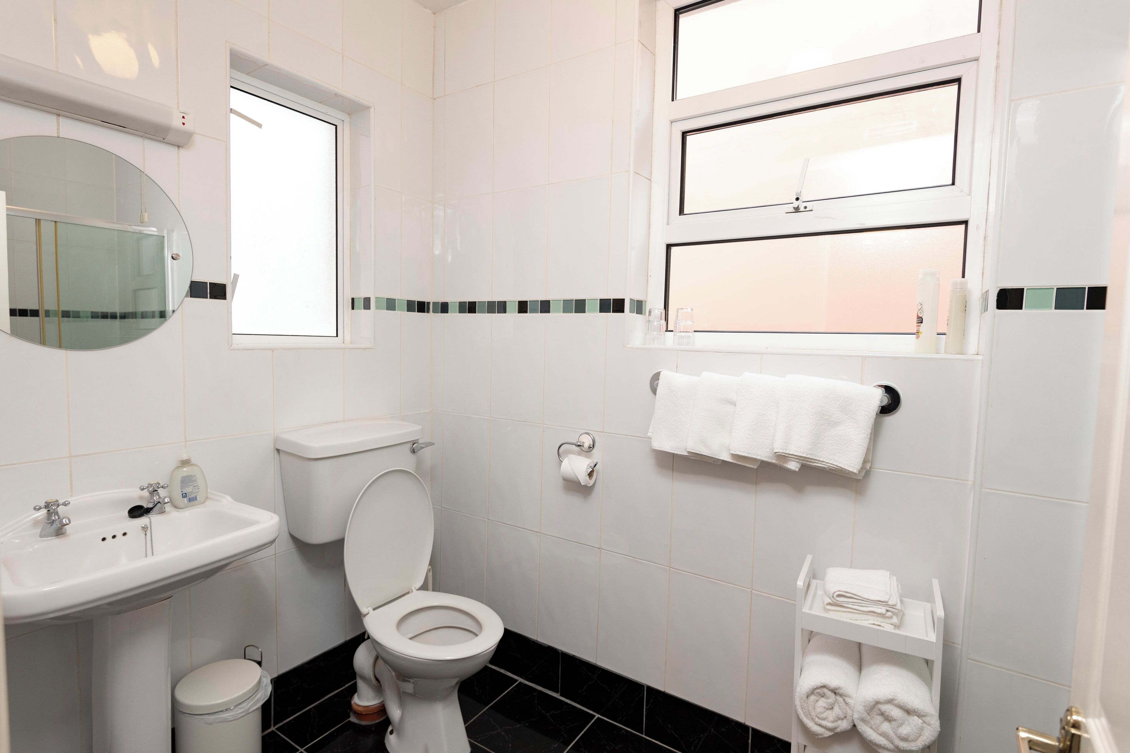 A bathroom with a toilet, sink, mirror, and towel rack.