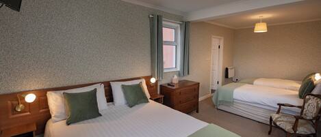 A hotel room with a large bed, a smaller bed, a nightstand, a chair, and a window.