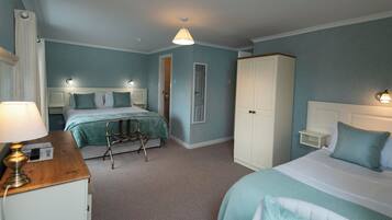 A hotel room with two beds, a wardrobe, a bedside table, and a lamp.