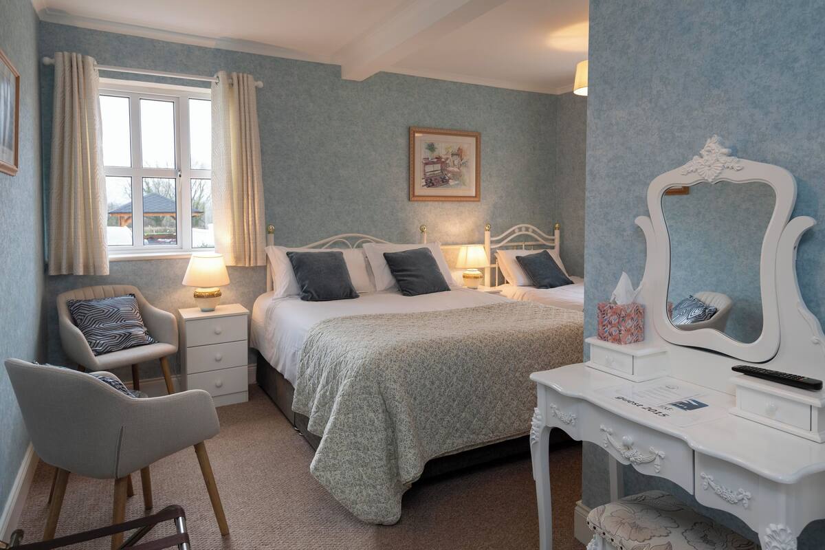 A bedroom with a bed, bedside tables, a chair, a dresser, and a window with curtains.