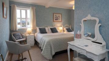 A bedroom with a bed, bedside tables, a chair, a dresser, and a window with curtains.