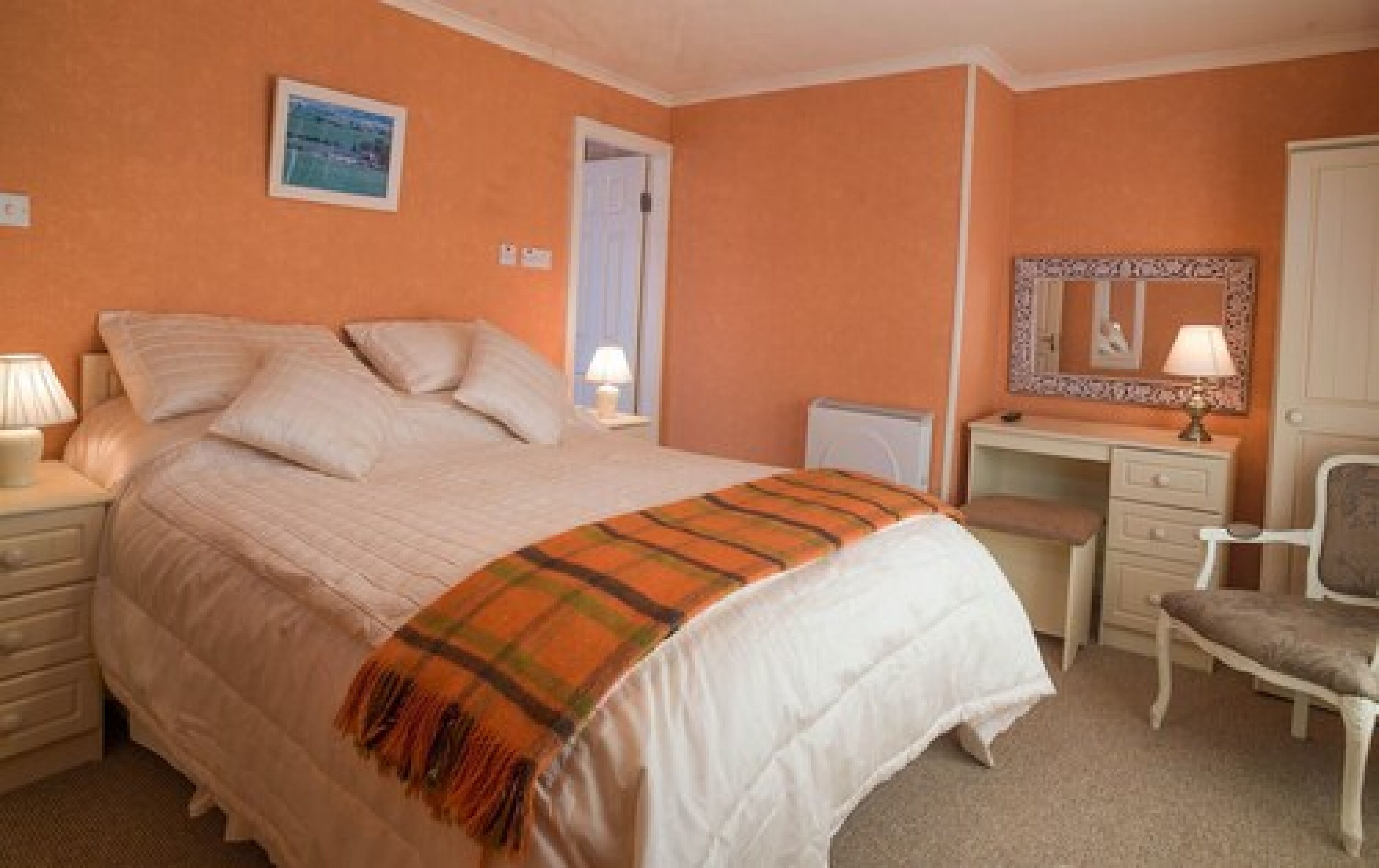 A bedroom with a bed, a desk, a chair, and a mirror.