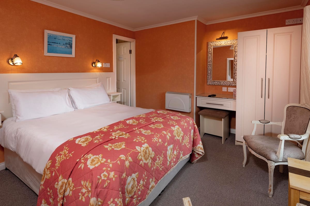 A hotel room with a bed, a desk, a chair, and a wardrobe.