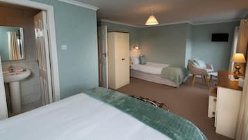 Ett hotellrum med en säng, ett skrivbord, en stol, en garderob, en spegel och ett badrum med handfat och toalett.