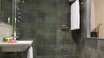 Et moderne badeværelse med brusekabine i glas, håndvask med toiletartikler, en bidet og et toilet.