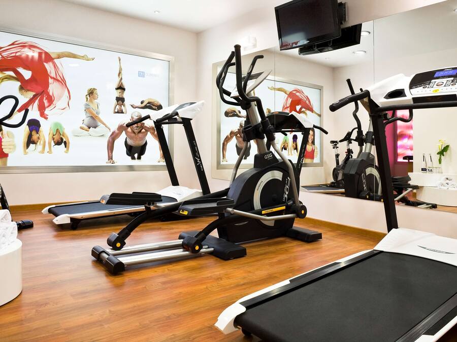 Ein Fitnessstudio mit unterschiedlicher Trainingsausstattung, darunter Laufbänder und Ergometer.