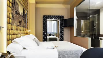 Ein Hotelzimmer mit Bett, Fernseher, Dusche und einem an der Wand hängenden Bild.