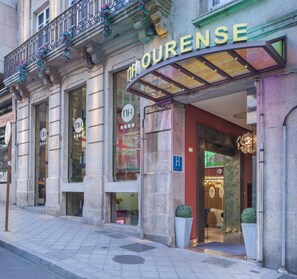 A hotel entrance with a glass canopy, a sign reading "HOURENSE", and a wheelchair-accessible entrance.