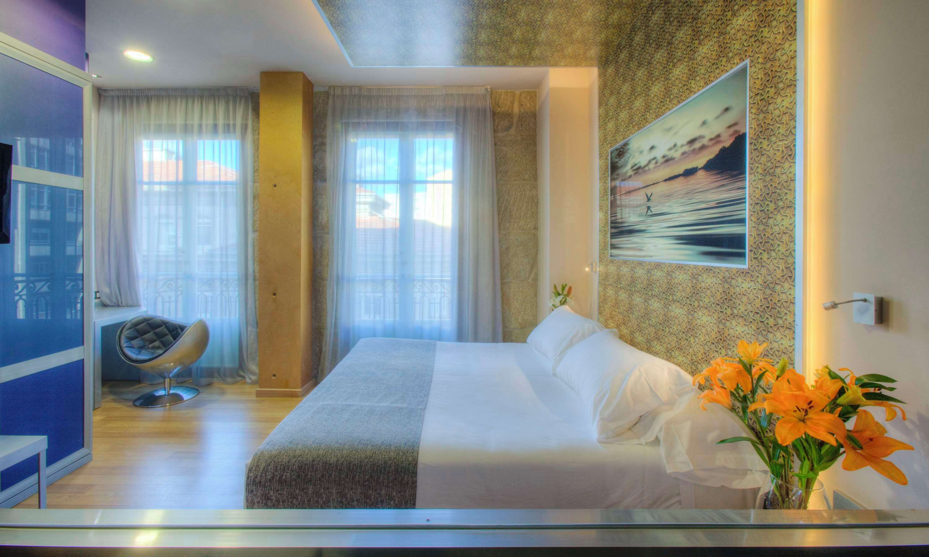 Habitación de hotel con una cama grande, una silla, un escritorio y vistas al exterior.