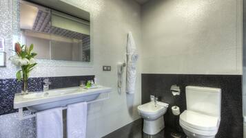 Un baño moderno con un espejo grande, un lavabo, un bidé y un inodoro.