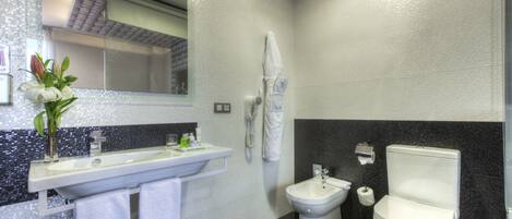 A modern bathroom with a large mirror, a sink, a bidet, and a toilet.