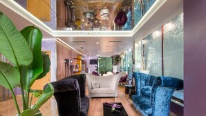 A spacious, modern interior with a high ceiling, a central seating area with a sofa and chairs, and a large potted plant. - NH Ourense (Ourense)