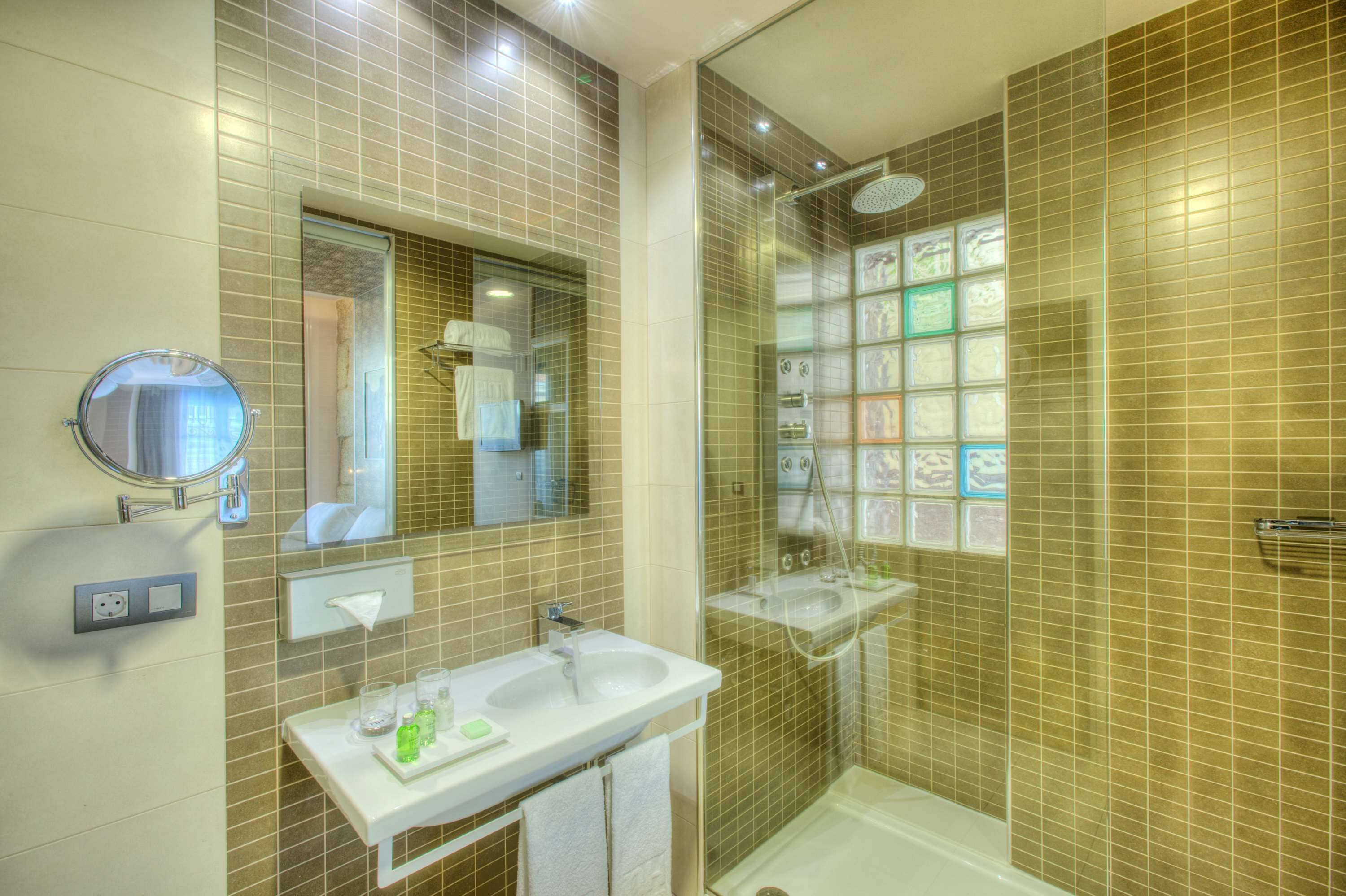 A bathroom with a shower, a sink, a mirror, and a towel rack.