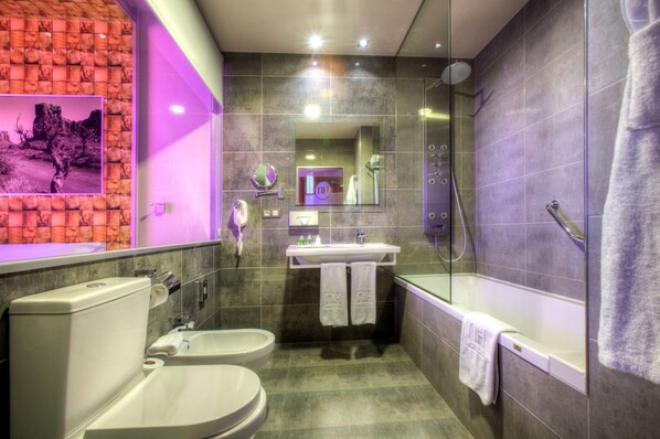 Un baño moderno con un bidé, un lavamanos y una bañera.