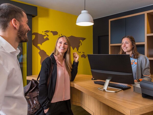 A reception desk with a computer and keyboard, a world map on the wall, and a hanging light fixture.