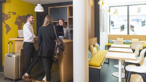Un hall d’hôtel moderne avec un comptoir d’accueil, un espace salon et une carte du monde accrochée au mur.