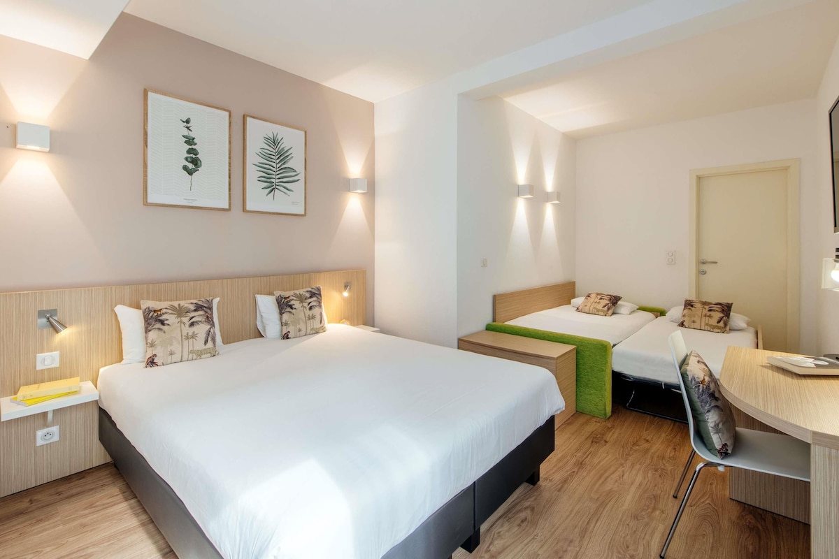 Habitación de hotel con dos camas, un escritorio y una silla.