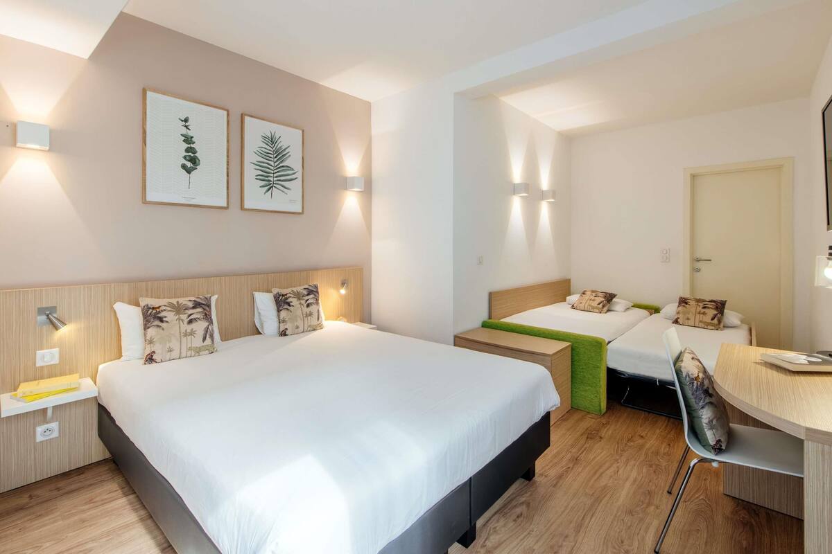 A hotel room with two beds, a desk, and a chair.