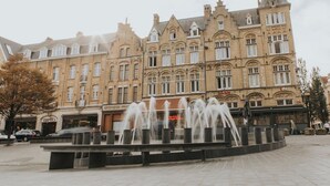 A historic building with a fountain in front, likely a hotel or public building. - Hotel New Regina (Ypres)