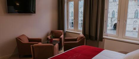 Habitación de hotel con cama, televisor montado en la pared y vista a un edificio histórico por la ventana.