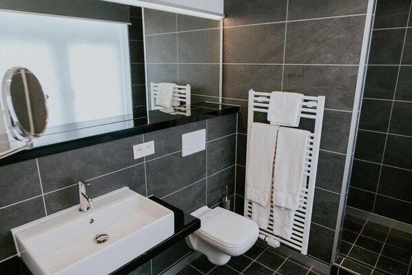 Un baño moderno con lavamanos de encimera negro, inodoro blanco y un perchero para toallas.