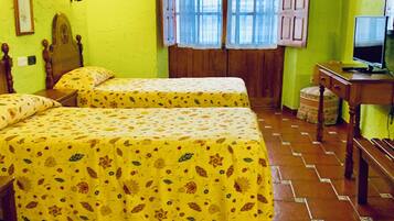Una habitación con dos camas, un escritorio con computadora y una ventana con cortinas.