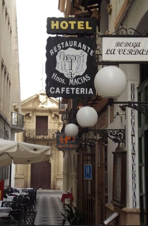 A narrow street with a hotel sign, a restaurant sign, and a cafe sign.