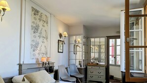 A hotel room with a bed, a desk, a chair, a dresser, and a large window. - Hôtel Entre Terre et Mer (Honfleur)