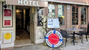 A hotel entrance with a sign reading 'ENTRE TERRE et MER HOTEL,' a menu board, and a lifebuoy with 'TERRE & MER OYSTER BAR' text. - Hôtel Entre Terre et Mer (Honfleur)