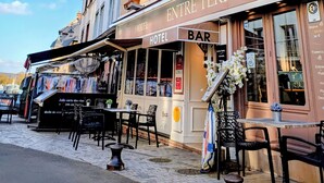 A hotel with a bar named 'Bar A Huitres' and 'Entre Terre et Mer' signs, outdoor seating, and a cobblestone street. - Hôtel Entre Terre et Mer (Honfleur)