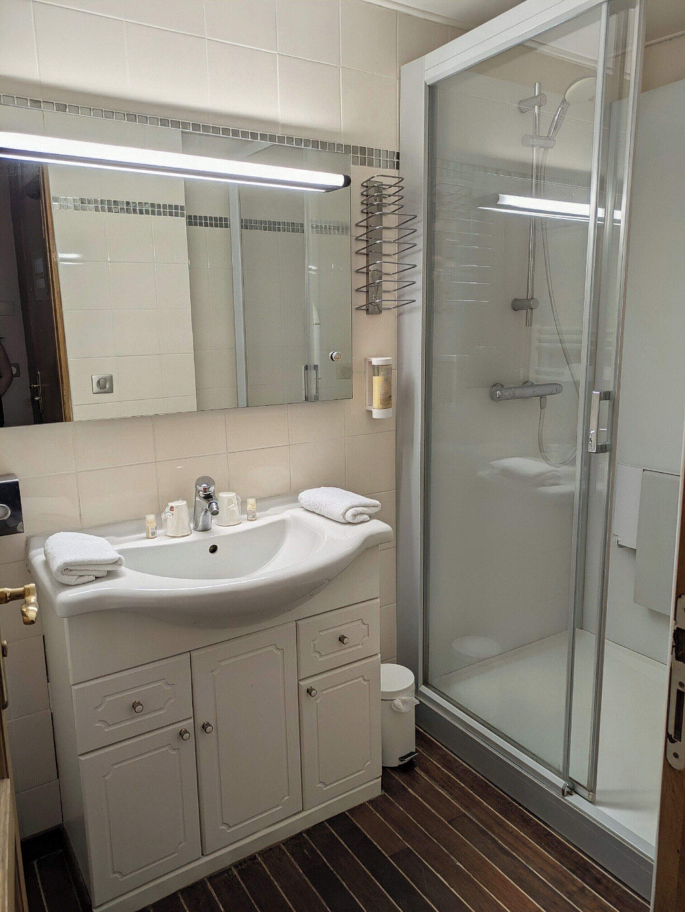 Un baño con lavamanos, espejo y ducha blancos.