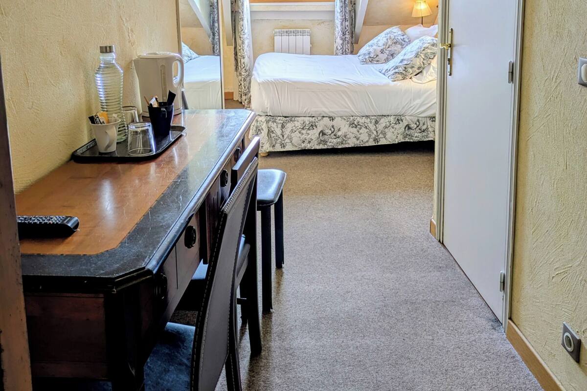 Une chambre à coucher avec un lit, un bureau, une chaise, une lampe et une fenêtre.