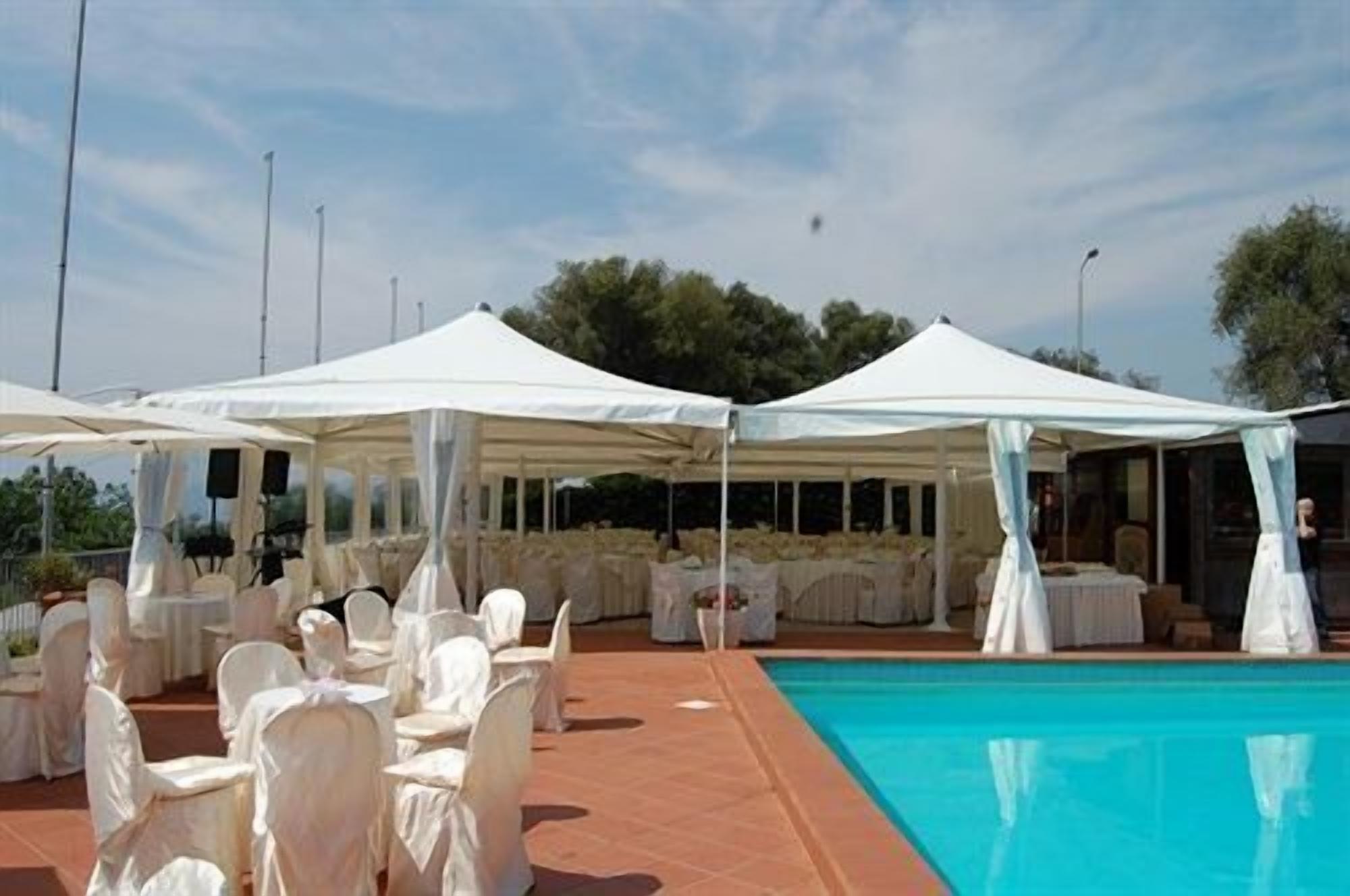 Un espace aménagé au bord de la piscine, avec des parasols blancs et des tables rondes, évoquant une ambiance élégante en plein air.