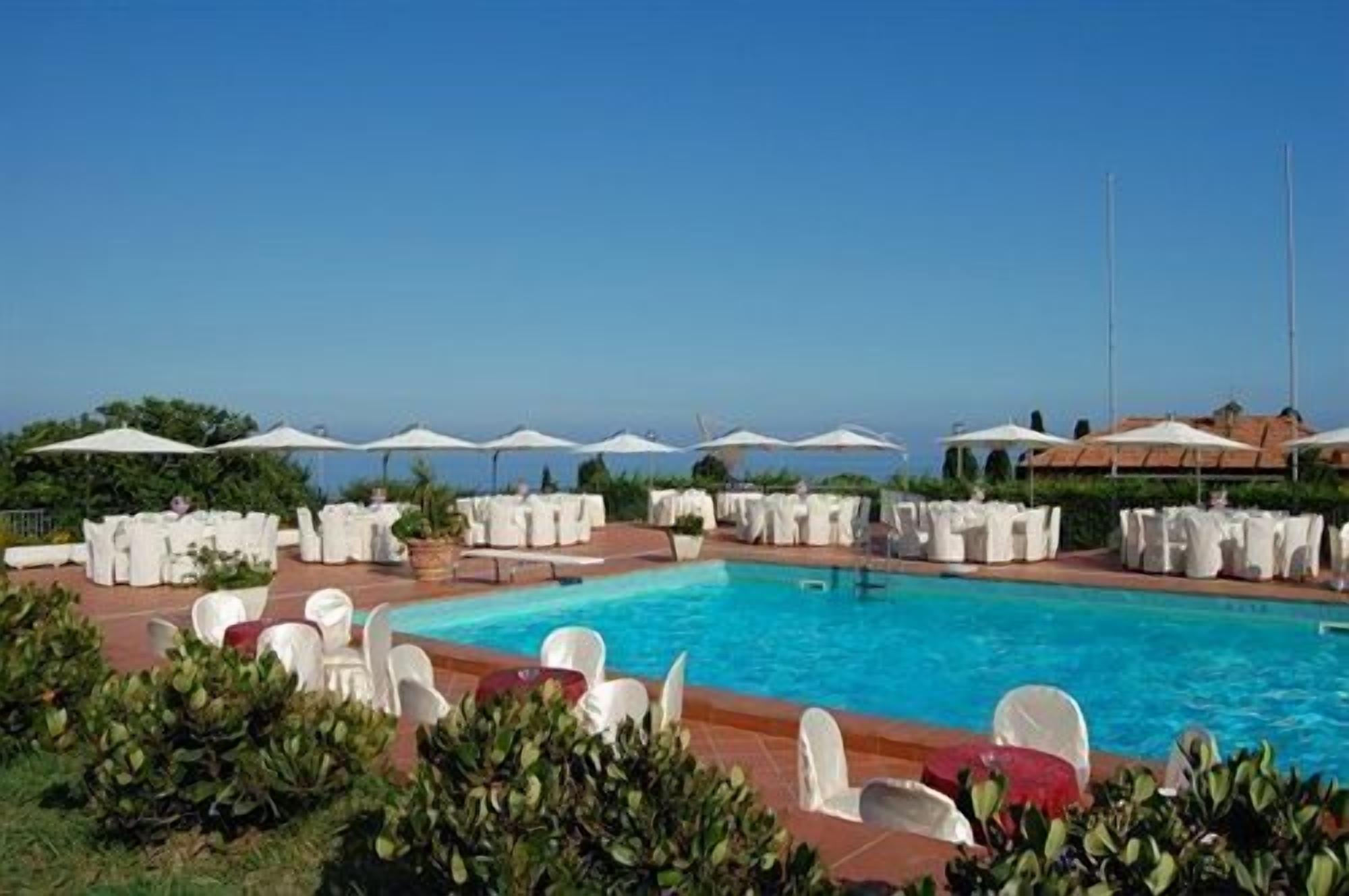 Una piscina al aire libre, sombrillas, sillones reclinables de piscina