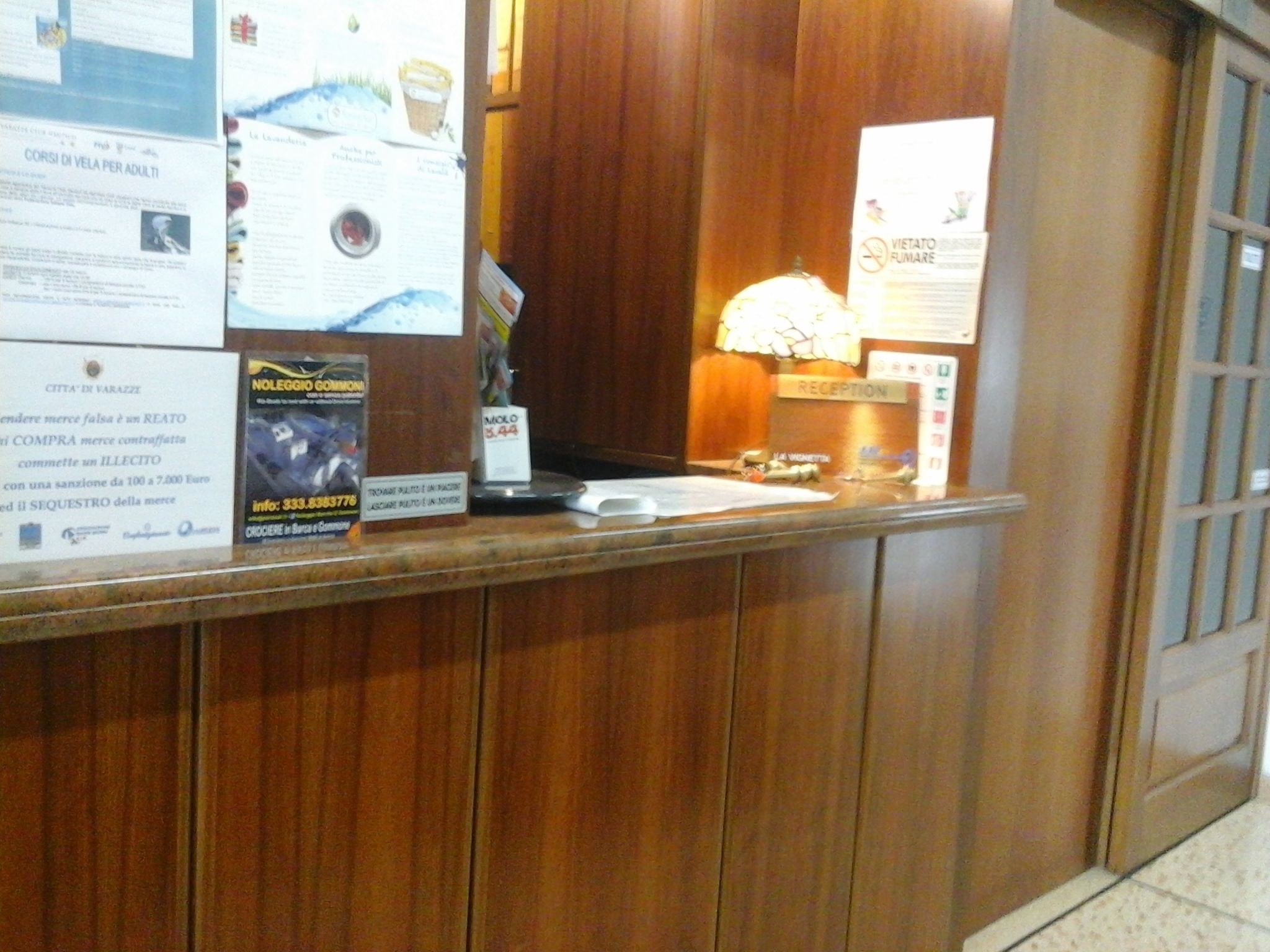 A reception desk with wooden paneling, a lamp, and various informational posters.