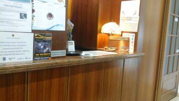 A reception desk with wooden paneling, a lamp, and various informational posters.
