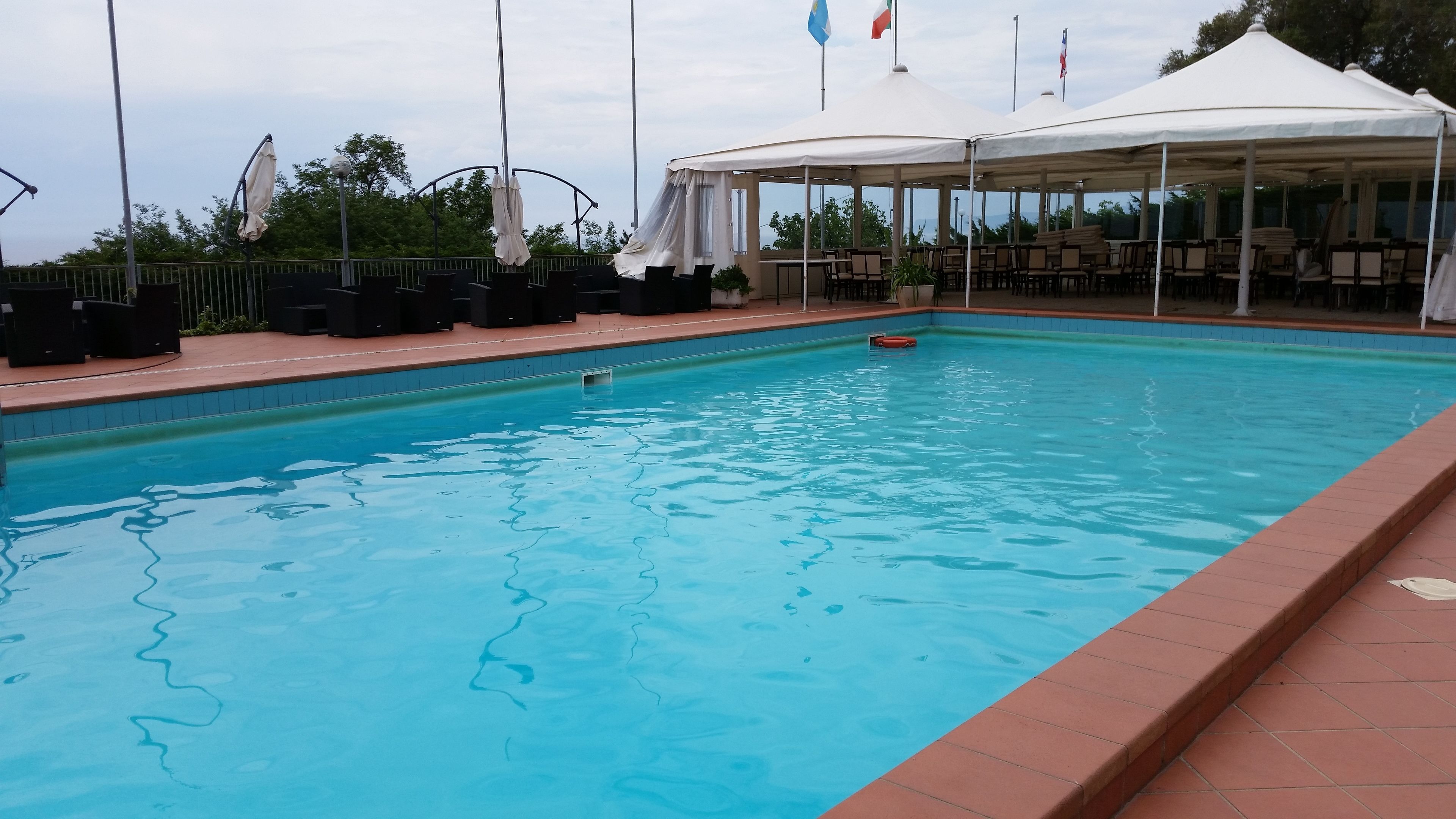 Ein Schwimmbad mit Liegestühlen und einer überdachten Sitzgruppe.