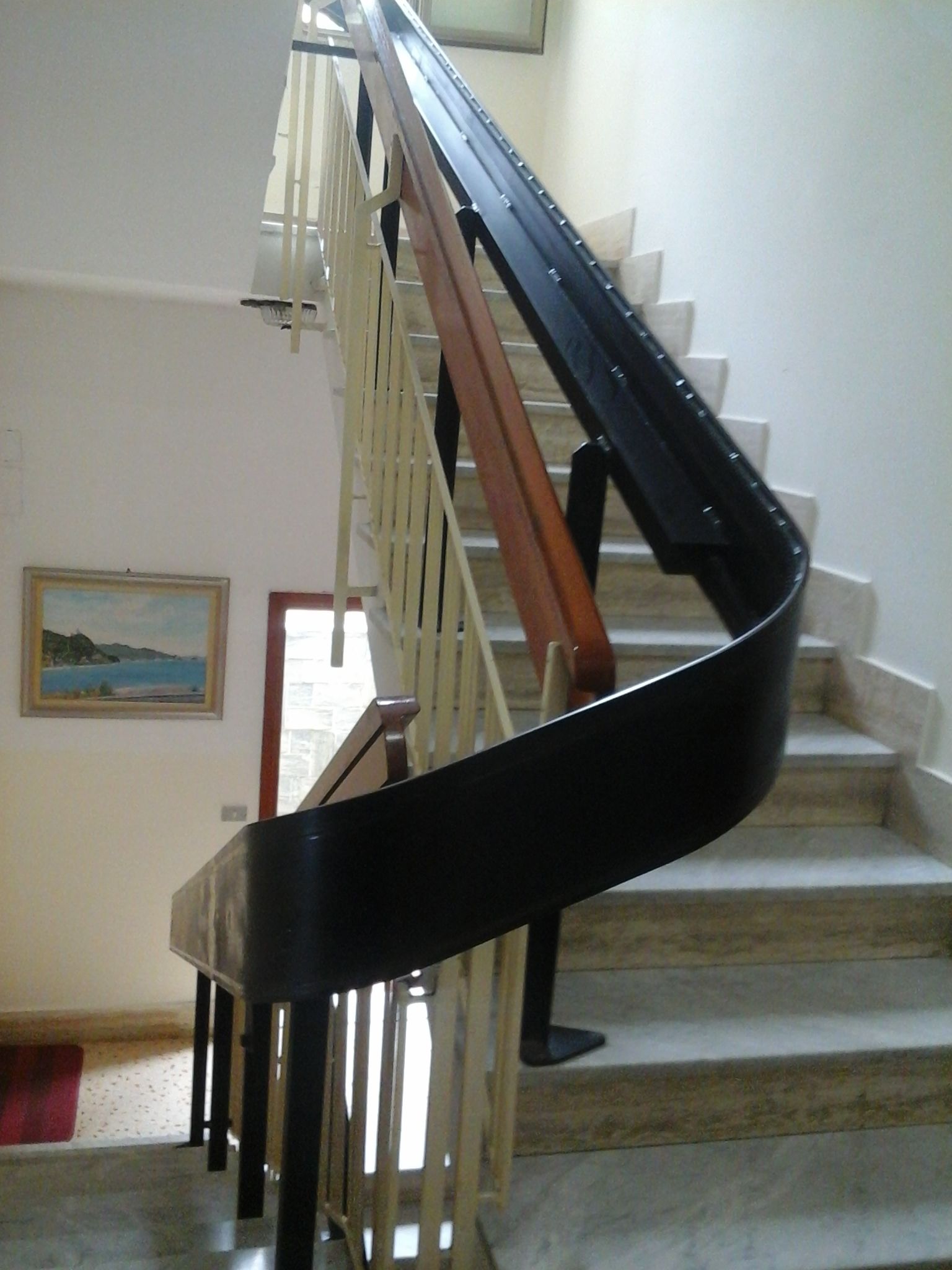 A spiral staircase with a black handrail and wooden steps.