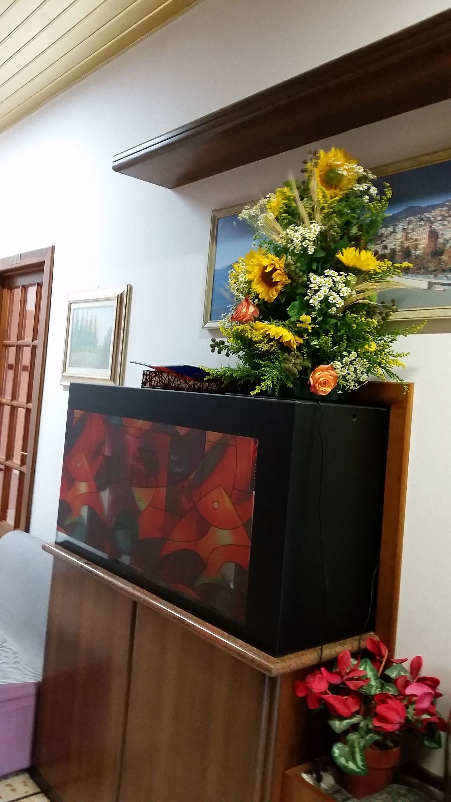 Een kamer met een houten bureau, een lijst met een schilderij en een bloemenboeket.