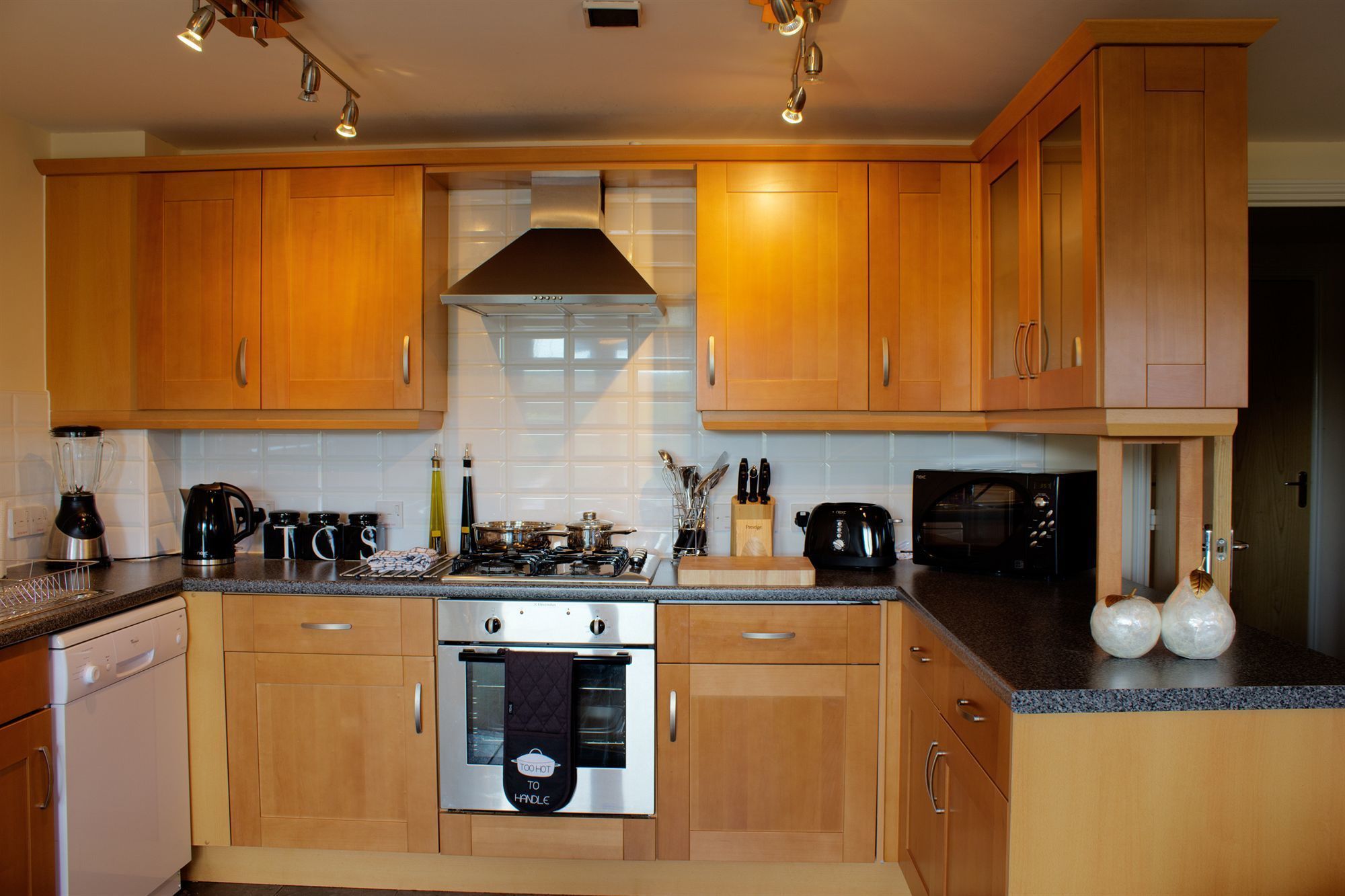 Een moderne keuken met houten kastjes, een rvs-fornuis en een magnetron.