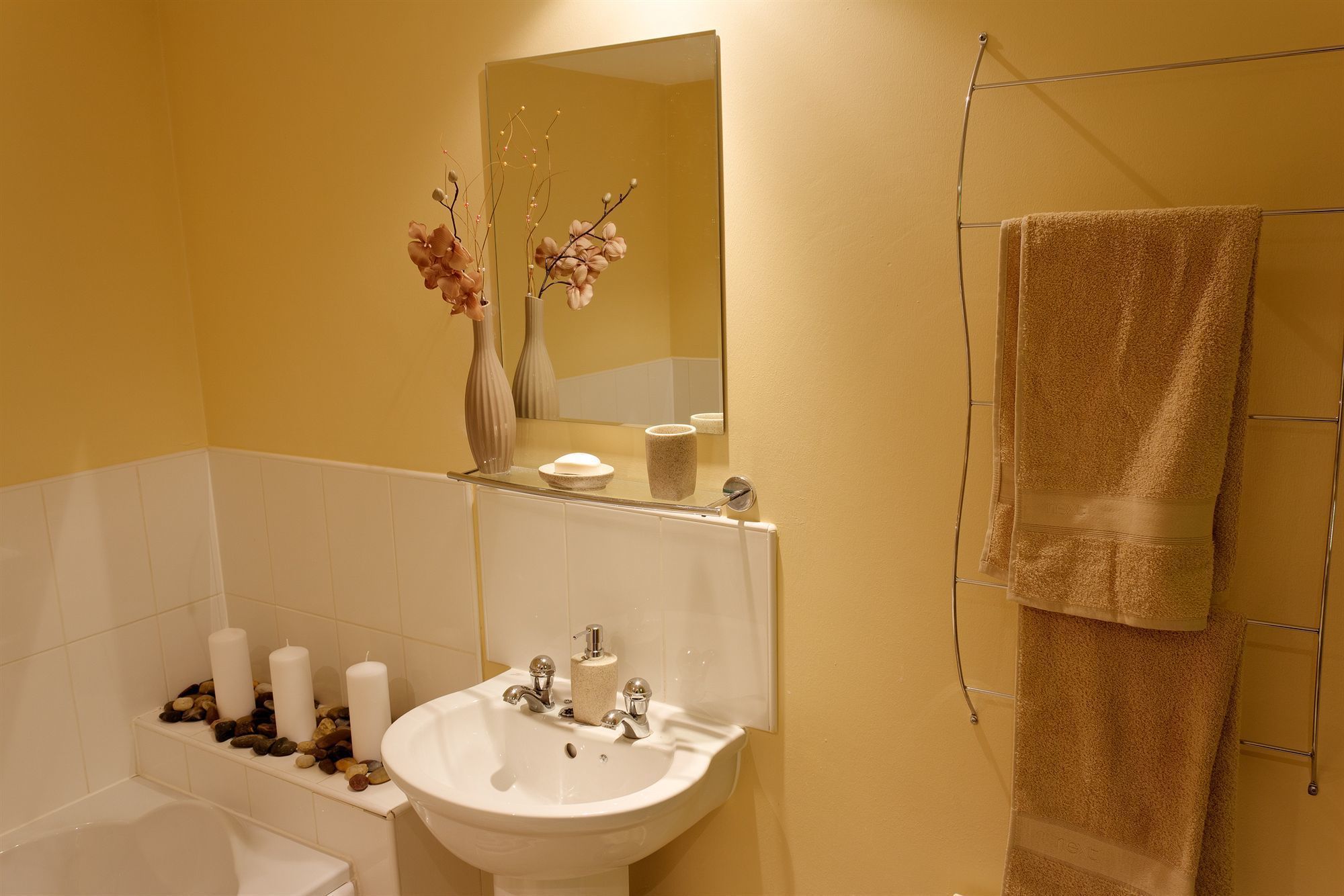 A bathroom with a white sink, a mirror, and a towel rack.