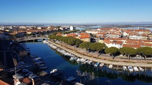 A marina with boats docked, a bridge, and buildings with red roofs. - Residence Hotel Hungaria (Grado)