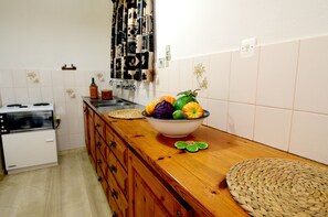 Una cucina con piano di lavoro in legno, una ciotola di frutta, un fornello e uno schienale piastrellato.
