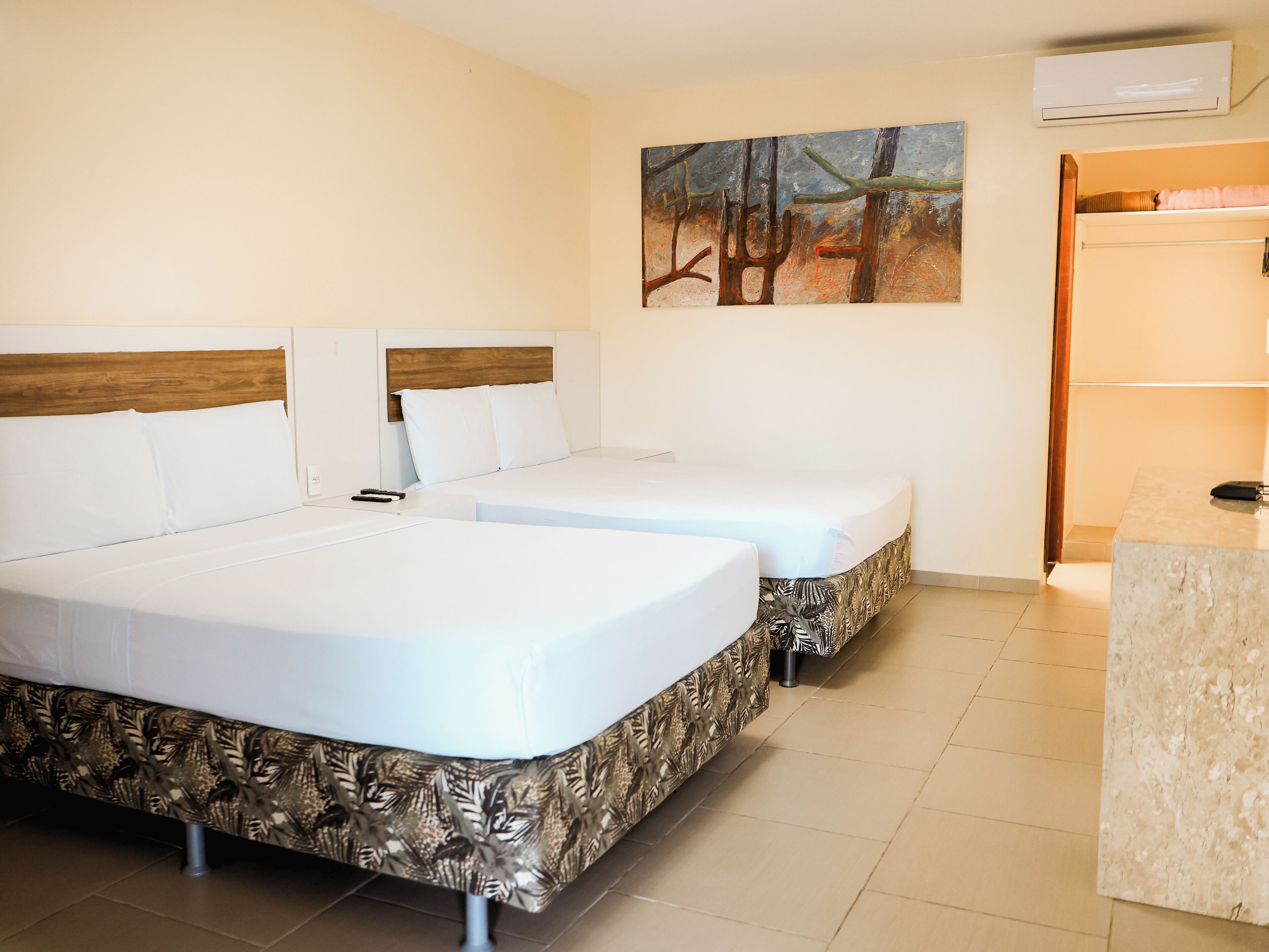 A hotel room with two beds, a painting on the wall, and a marble counter.