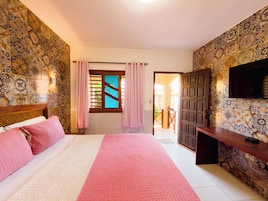Una habitación de hotel con cama, televisión, escritorio y vistas al exterior.