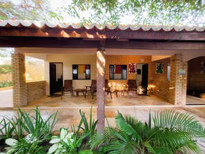 A covered outdoor seating area with brick walls, a tiled floor, and potted plants. - Pousada Jardim dos Orixás (Aracati)